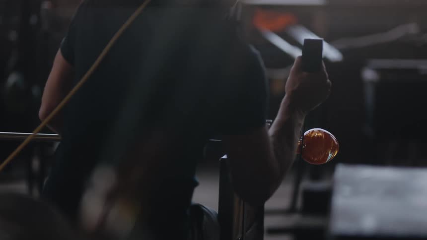 A man is forming glass with tools