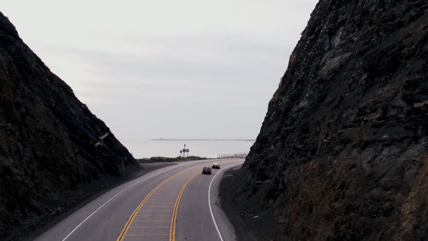 Cars are driving on a road in between to mountains