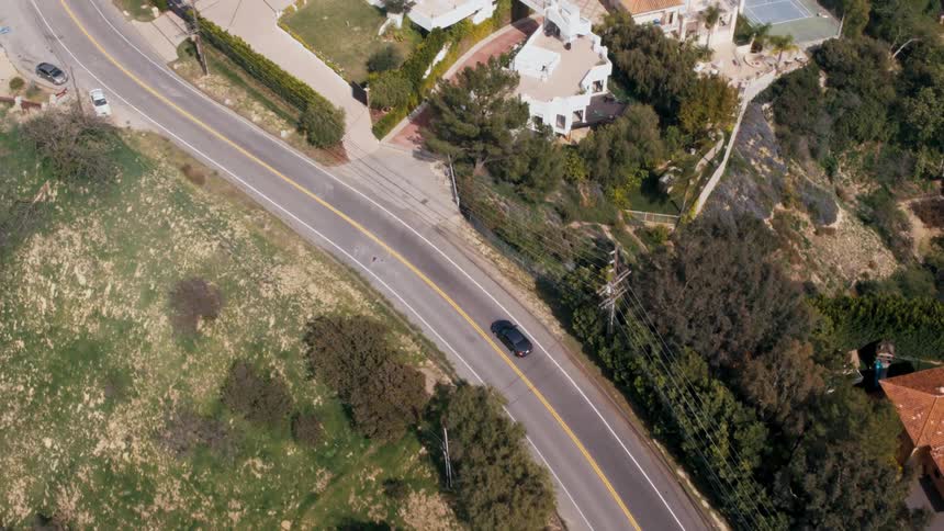 A car is driving on a road through a suburban area
