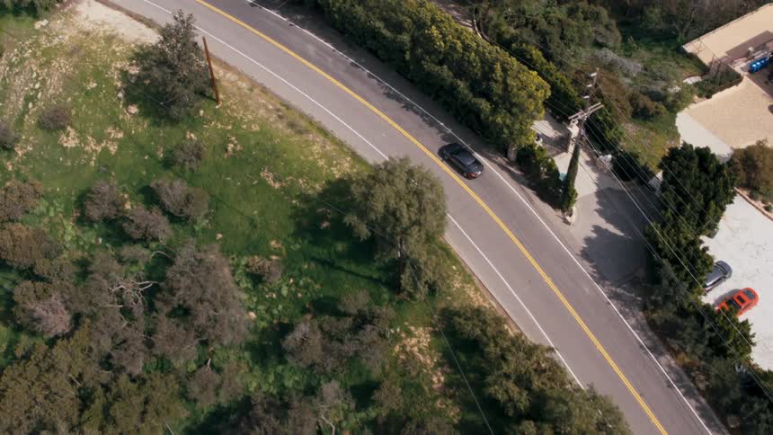 A car drives on a street past houses in a neighborhood