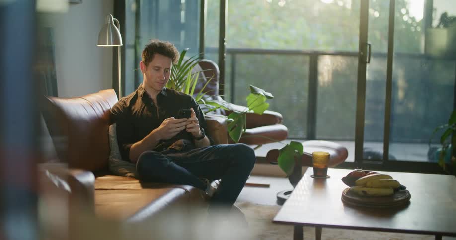 A man drinks from his glass while using a cell phone