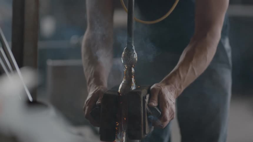 Glass blower cooling hot glass with steam coming off in artisan studio