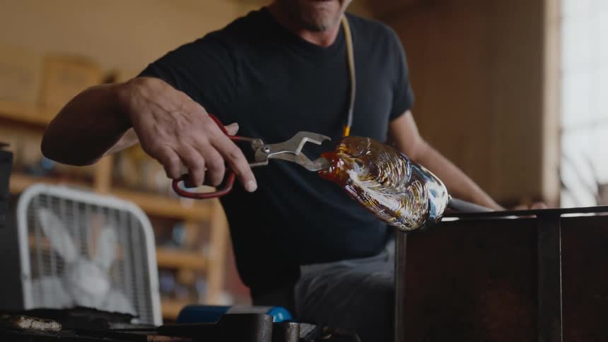 Handsome artist bending and shaping a colorful vase