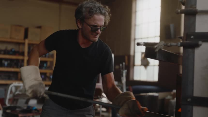 Artist working hard to shovel hot glass