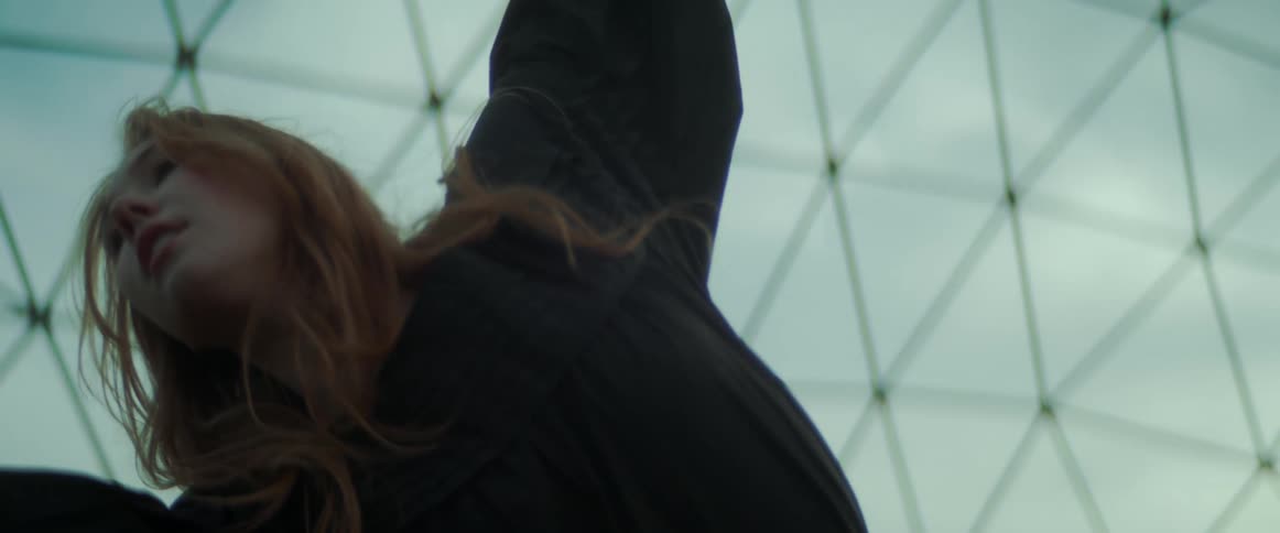A woman dances under a glass dome on a sunny bright day