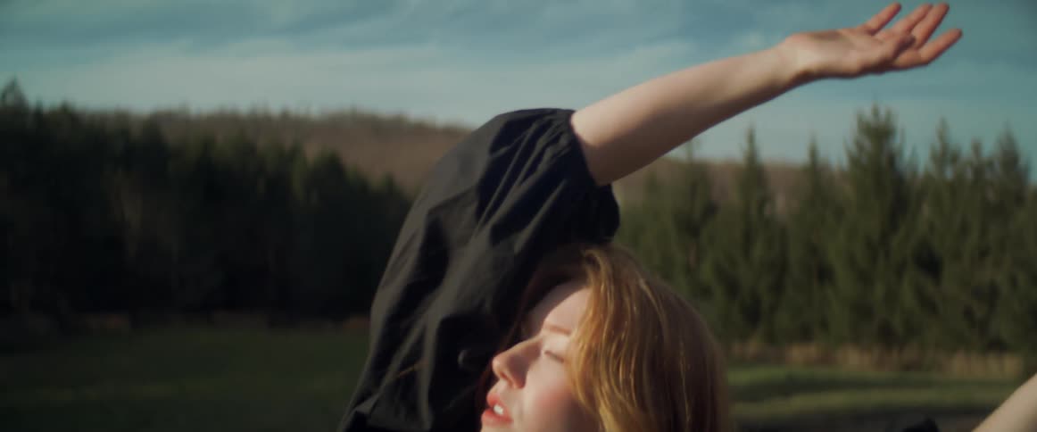 A woman is dancing outdoors in the wilderness during spring
