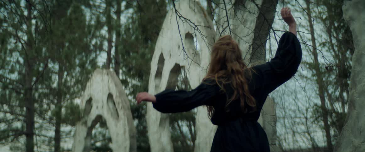 A woman is dancing in a forest during the spring time