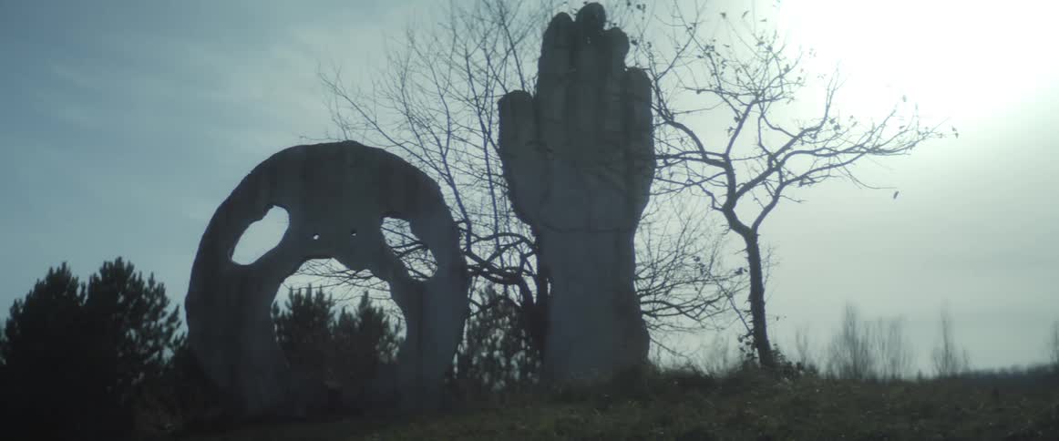 Statues are shown in a grassland area
