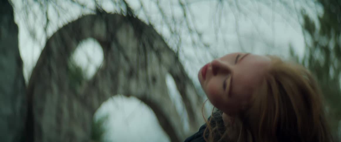 A woman is outdoors in a wooded area and dancing