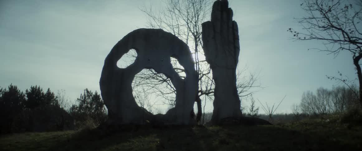 A scary statue of a face and hand are on the field
