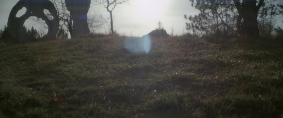 Sun shines onto sculpture on top of grassy hill