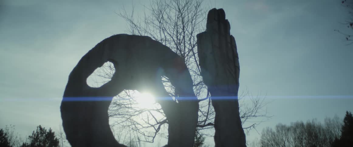 A statue of a hand and a large circle in a park