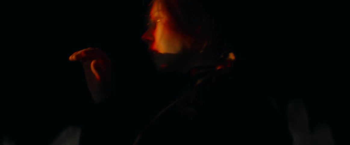 A woman dancing with emotion in a dark cave setting