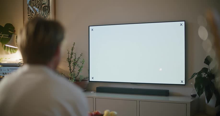 A man is sitting indoors and watching television