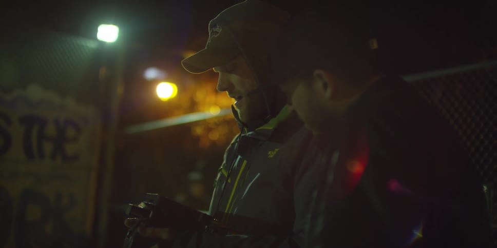 Two men look at a camera at night