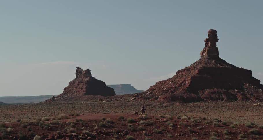 Man walks across scrub land in badlands on misty day