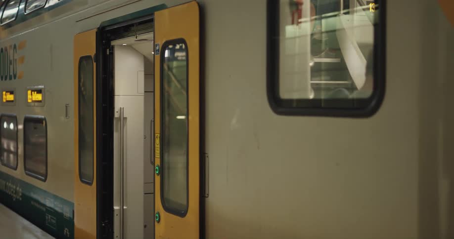 Blonde woman briefly boards train car before exiting and heading across terminal toward escalators