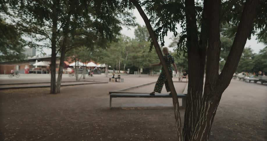 A woman is dancing on a bench in the middle of a park