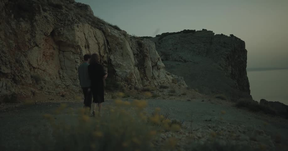 A man and woman are walking with a baby in nature by large rock formations