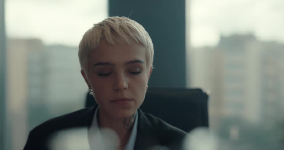 A tired woman sitting in an office stretches her neck before rubbing her forehead