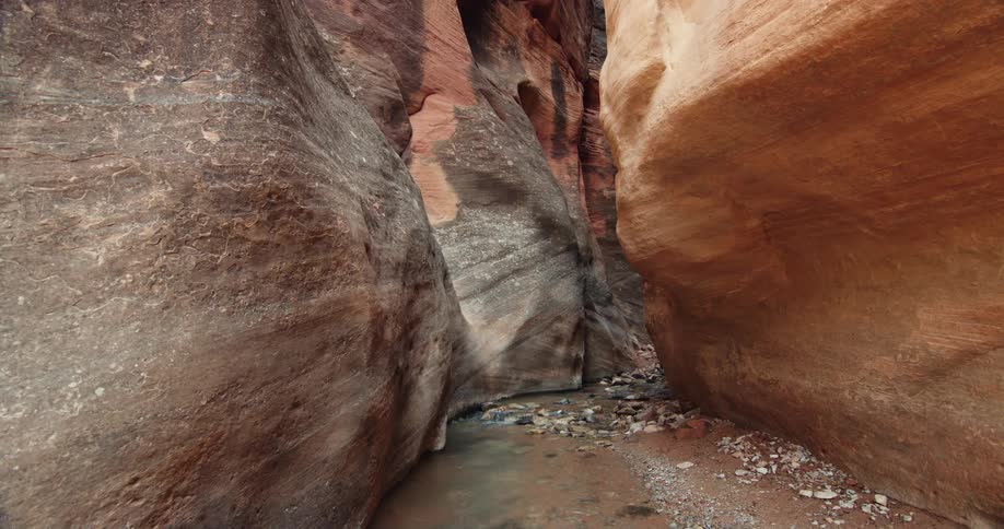 A small stream runs along the floor of a ravine during the day