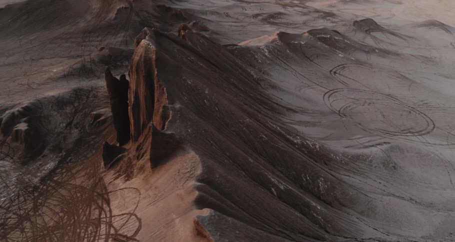 A mountain ridge and rock formations as the sun shines brightly on the horizon