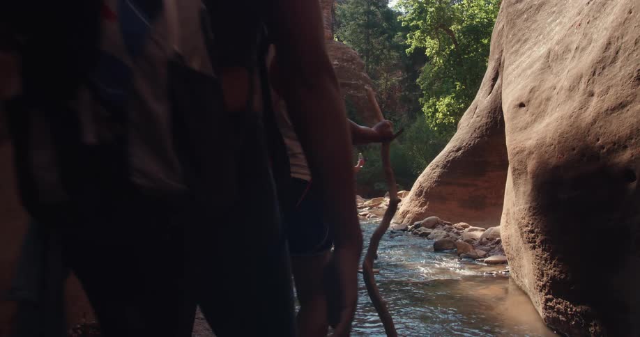 A group of people are hiking together through a creek