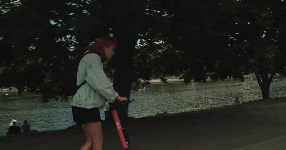 A young woman rides an electric scooter in a public park