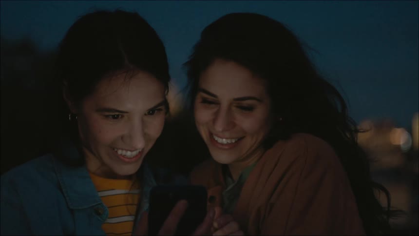 Two women look at a cell phone together