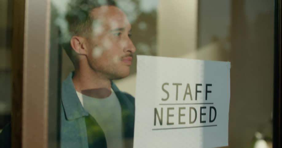 A man inside a business walks up to the window and hangs a sign