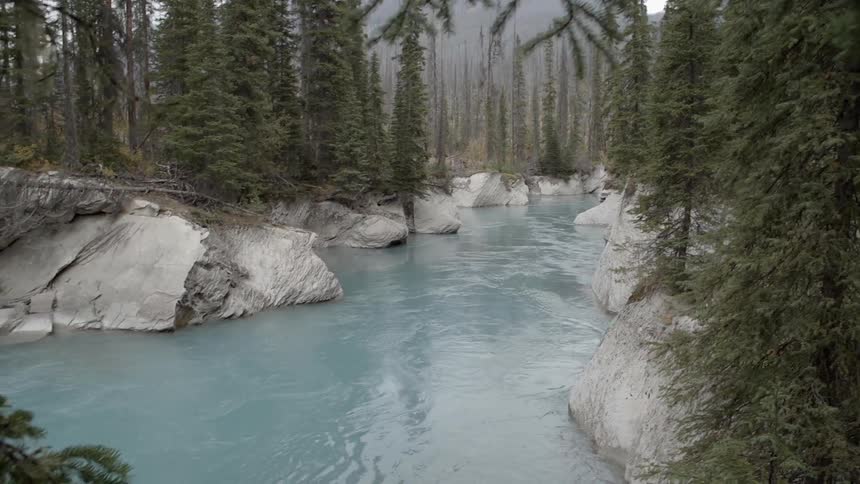 A stream has very blue water on a cloudy day