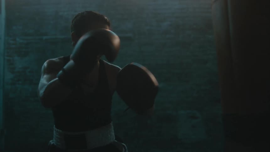 A woman is boxing by herself in an empty room