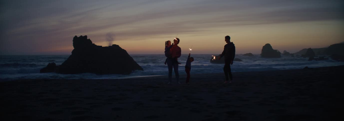 A family plays with sparklers on the beach