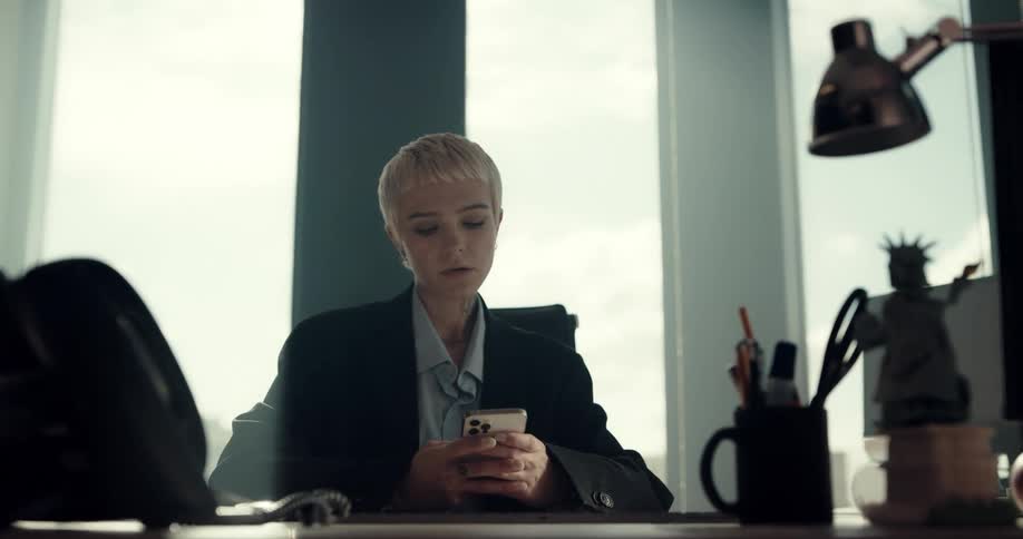 A woman is texting on her phone in her office