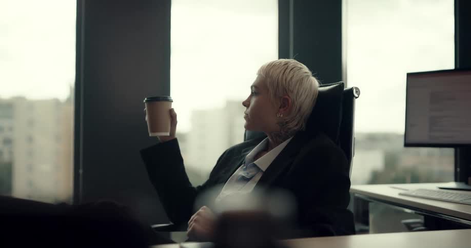 Woman is drinking coffee in her office near a window