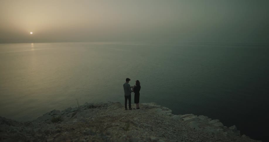 Woman and man are standing together by the ocean coast