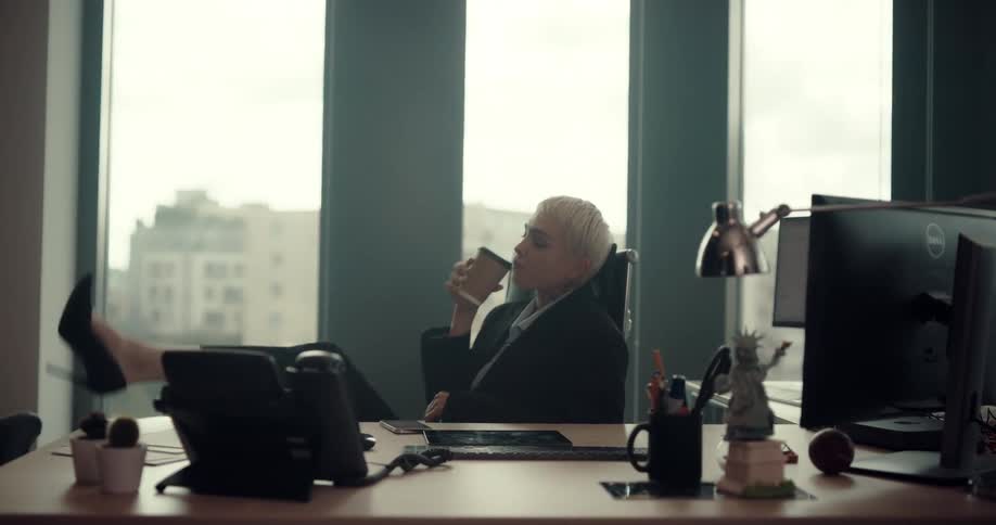 A woman is drinking coffee and sitting in her office