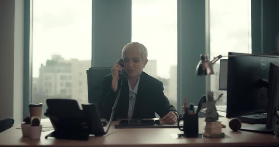 A woman works at her desk while talking on the phone