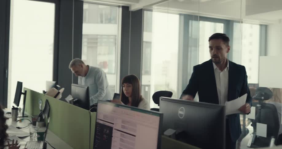 A man gathers paperwork from the employees then walks into another room to discuss