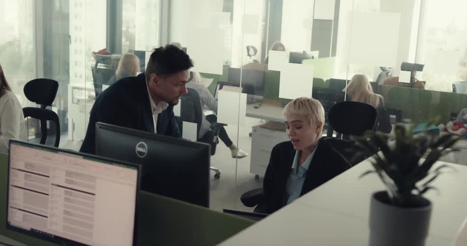A man is arguing with a woman at a desk in an office