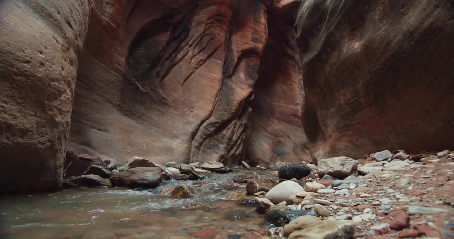 Calm shallow river flowing over the rocks through a narrow canyon or ravine