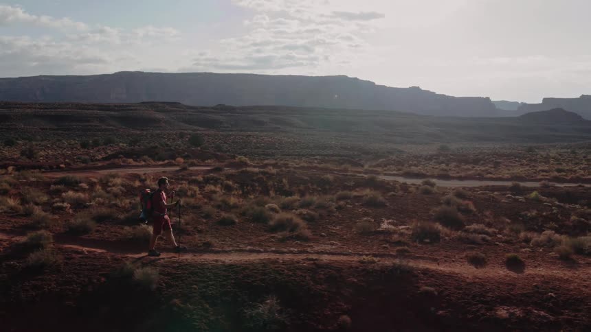Drone shot of a man hiking on a trail in the desert