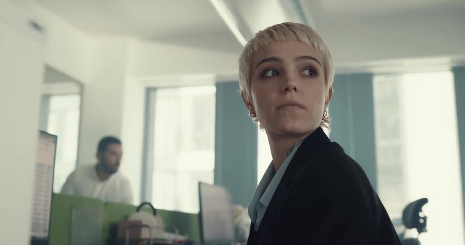 Young short haired blonde woman sitting on a desk working at the office
