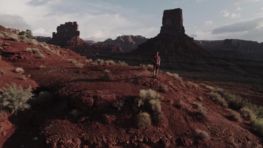 A man is hiking through a valley during the spring time
