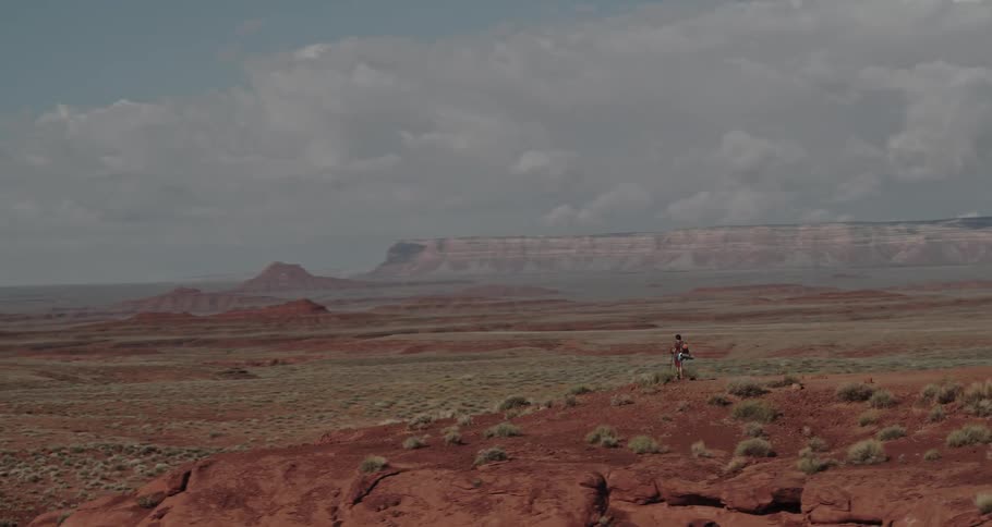 Hiker stands on plateau overlooking field and misty covered mountains on the horizon