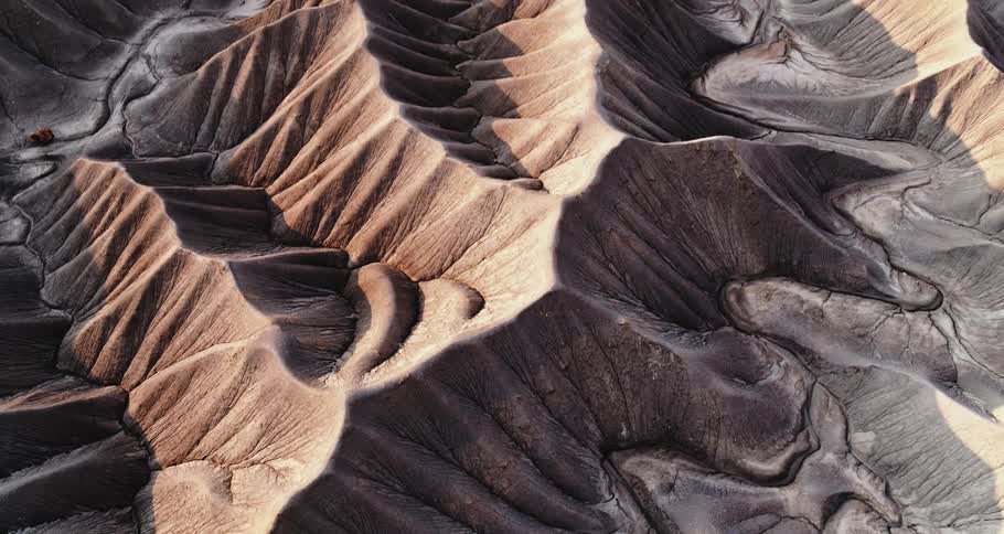 Arroyo run through low hills across desert and plains toward plateaus on the horizon