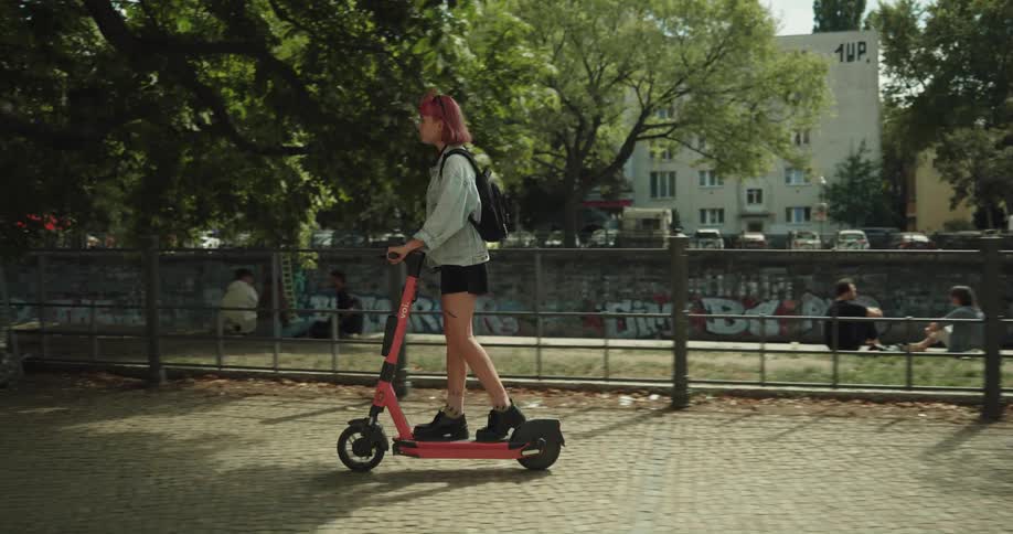 A female rides an electric scooter through a park setting
