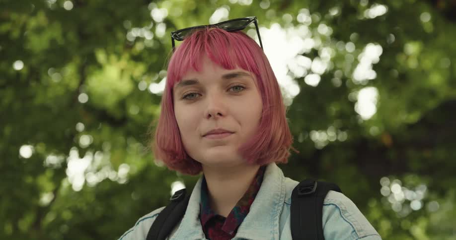 A woman smirks as she stands amongst the trees