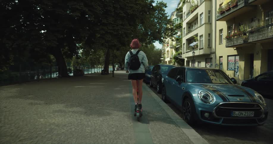 A woman is riding a scooter down the street