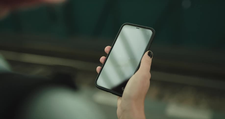 A female person is holding a cell phone and moving their thumb across the screen